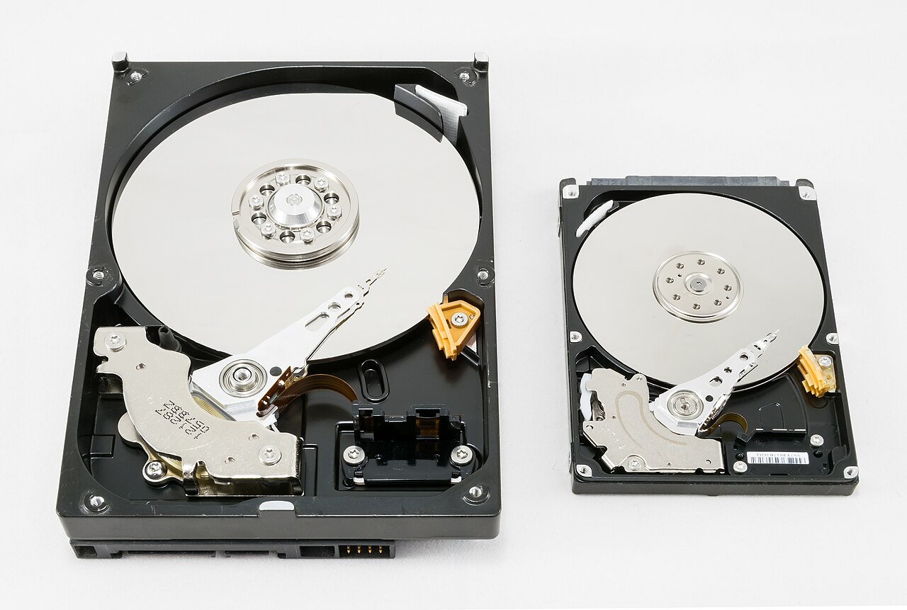 Two opened hard drives resting side by side, showing the platters and arms inside a storage device