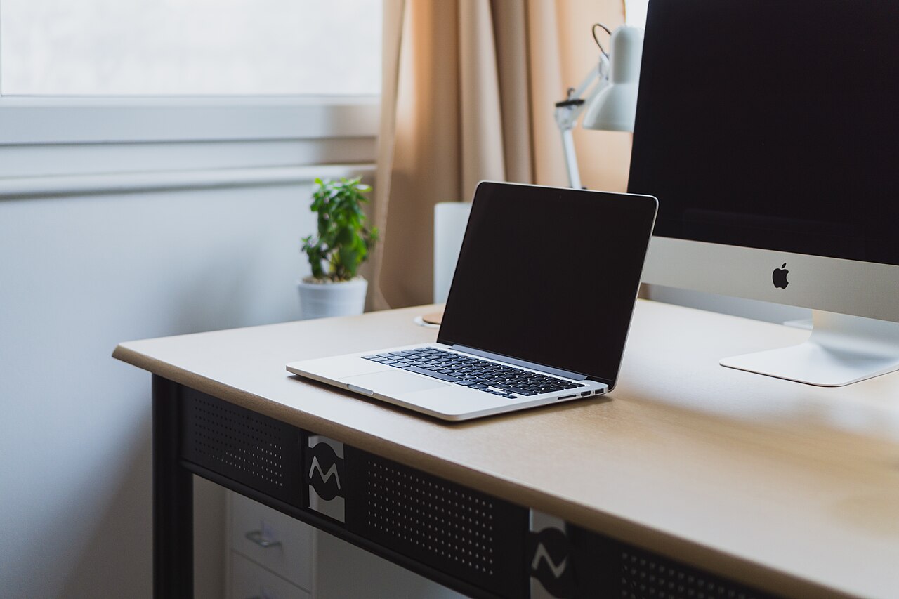 A tidy desk with an open laptop and a large display, the kind of calm workspace these guides are written for