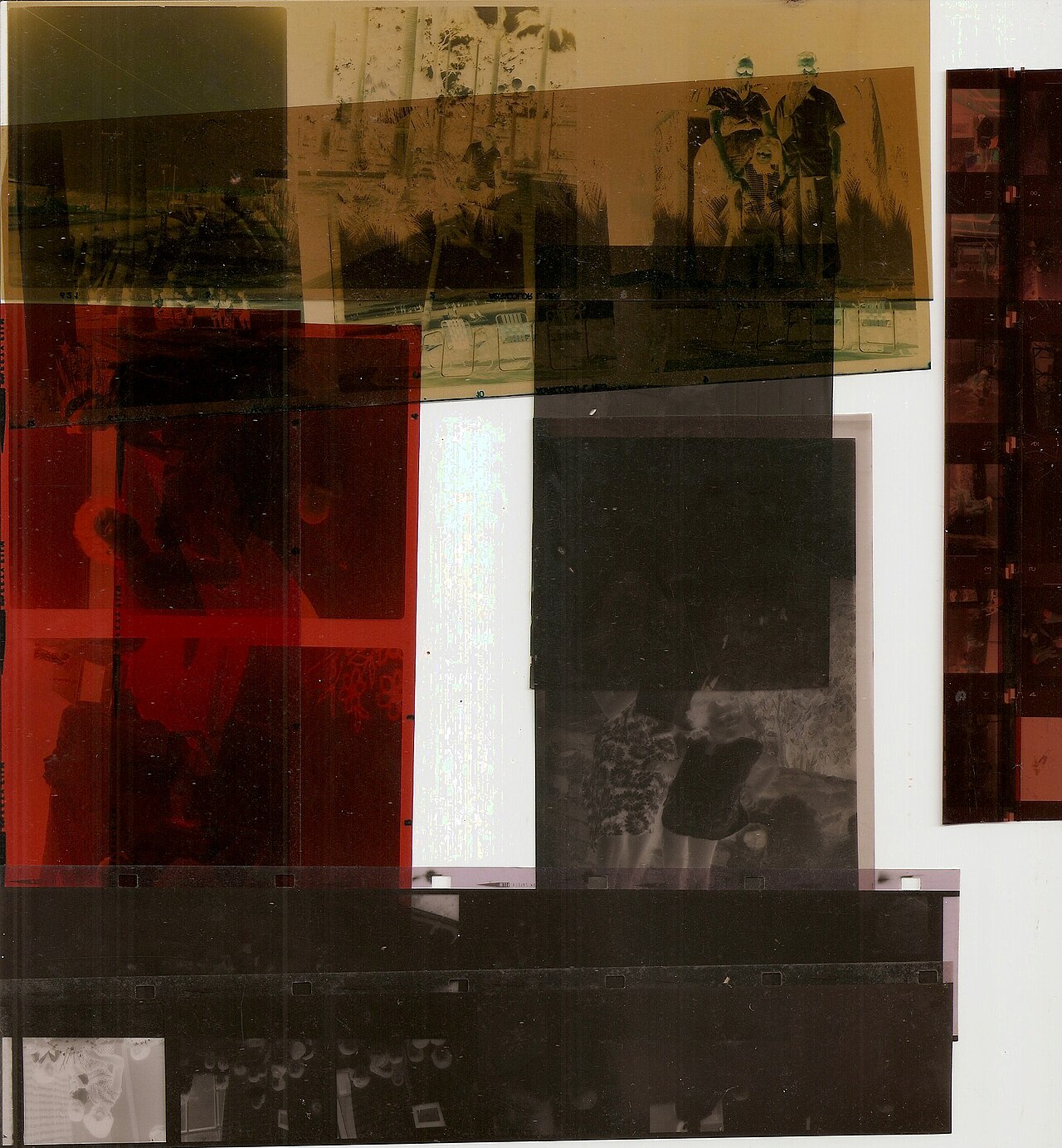 A strip of photographic negatives lying on a pale surface, with translucent frames showing landscapes and figures